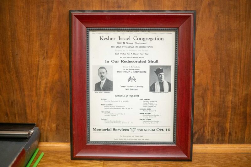 A 1954 flier advertising the synagogue’s High Holiday service offerings is framed in Kesher Israel’s social hall.